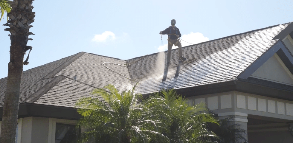 man on top of roof pressure washing
