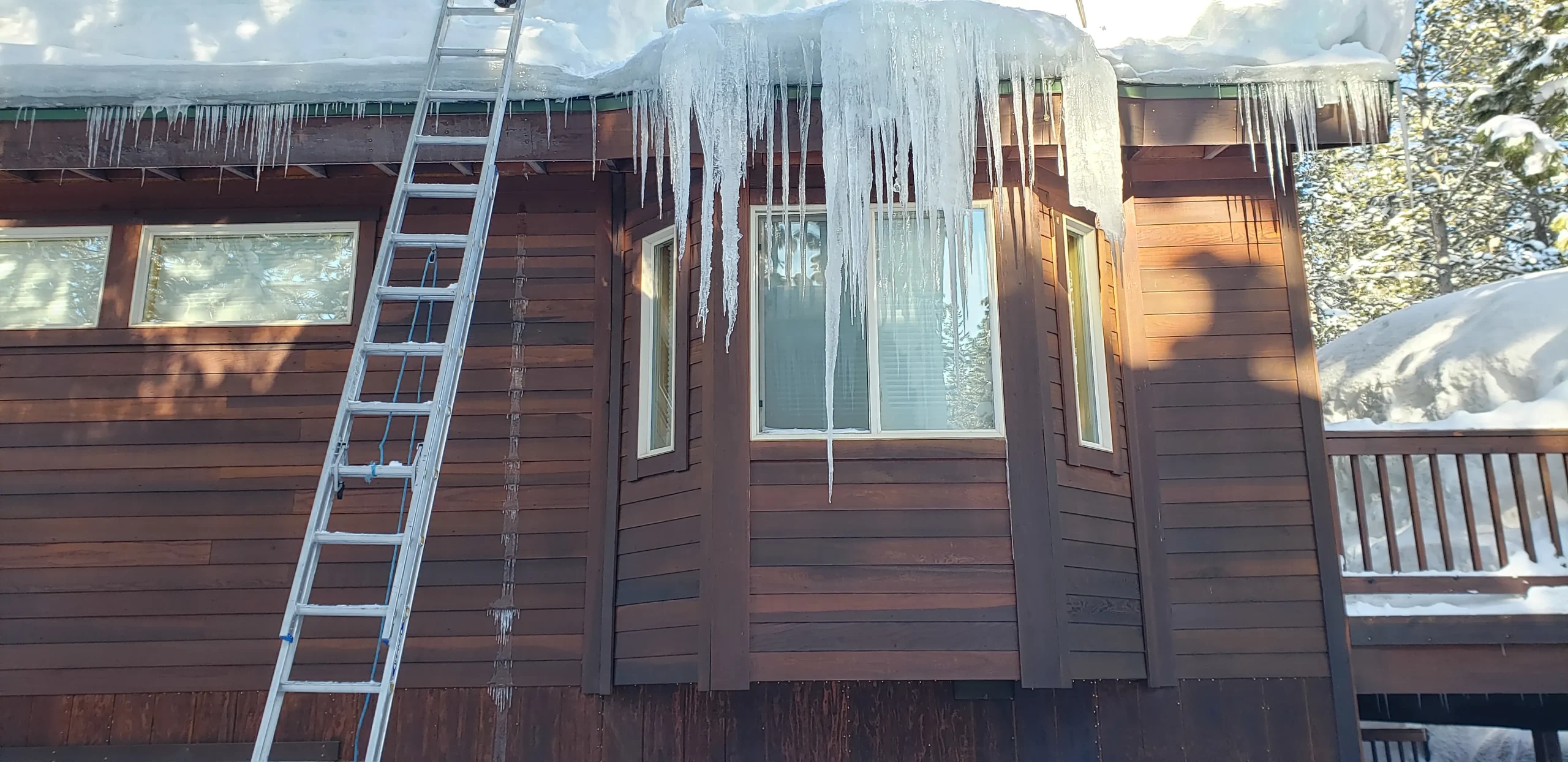 Severe ice dams and massive icicles forming on a Reno home's roofline, requiring professional ice dam removal services by Mills Roofing.
