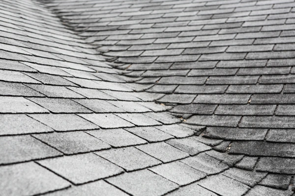 Asphalt shingle roof ridge showing granule loss and weathering over time