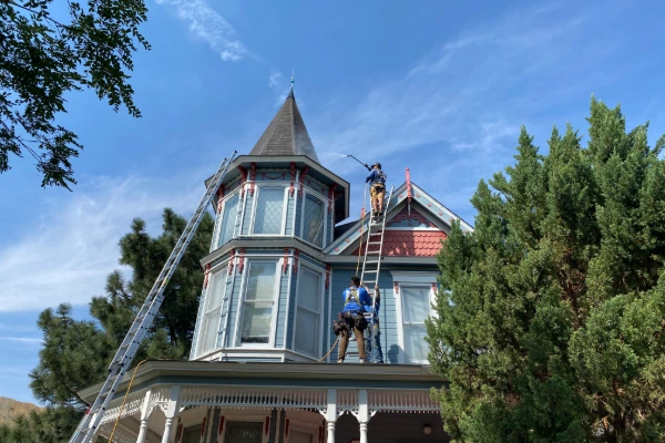 Mills Roofing crew applying Roof Maxx to a roof on a Victorian-style home