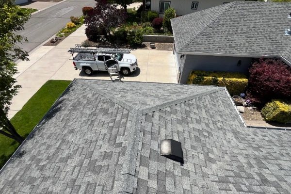 Aerial view of a completed asphalt shingle roof with a Mills Roofing truck in the driveway during a final roof inspection in Reno