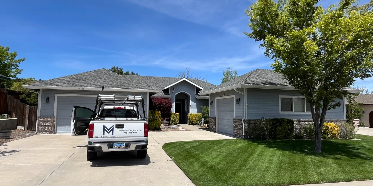 Mills Roofing truck parked in the driveway of a Reno home with a completed asphalt shingle roof replacement