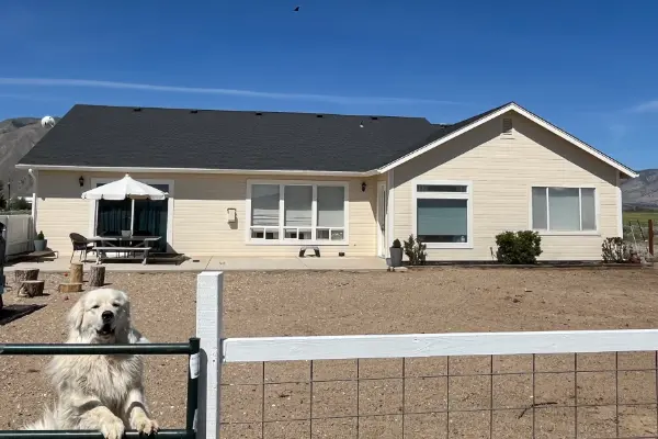 Completed asphalt shingle roof replacement on a Nevada home with Sierra Nevada mountain backdrop and clear blue skies.