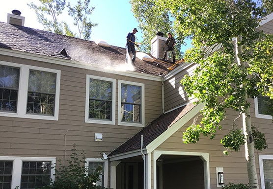 Mills Roofing employee sprays Roof Maxx on residential home
